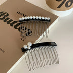 Two black hair combs with pearl embellishments are displayed on top of open books, one with a cluster of three pearls and the other with a row of pearls.