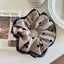 Beige polka dot scrunchie with black trim next to a newspaper