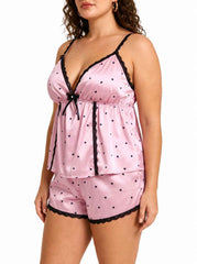 Side view of a pink satin cami and shorts pajama set with black heart print and lace trim.