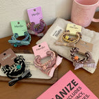 A collection of colorful hair ties with bows and braided details arranged on a table.