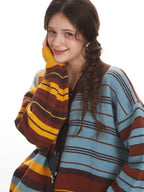 Close-up of a woman wearing a striped knit cardigan, touching her face and smiling.