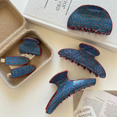 Various blue polka dot hair clips with red trim in a cardboard box and on a surface