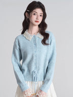 Woman wearing a light blue knit cardigan with a white lace collar and cuffs, paired with a white tiered maxi skirt.
