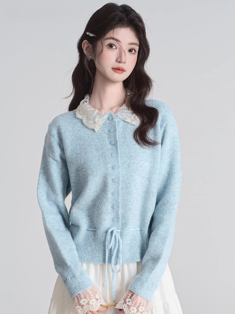 Woman wearing a light blue knit cardigan with a white lace collar and cuffs, paired with a white tiered maxi skirt.