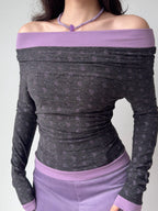 Front view of a woman in a grey and purple off-the-shoulder long-sleeve top, showing the neckline detail.