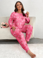 Woman wearing pink heart-print pajamas, sitting on a couch and holding a cup of coffee.