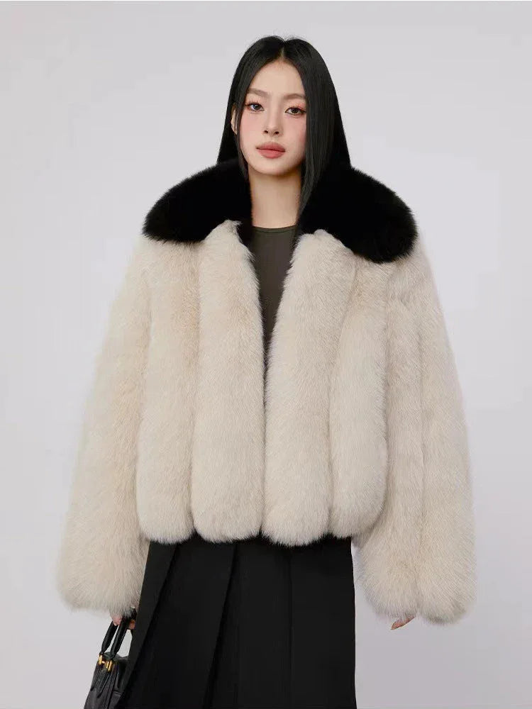 Woman wearing a cream faux fur cropped jacket with a black collar and a black dress. Main image