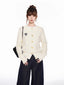 Woman wearing a cream cable knit cardigan with a heart patch and dark wide-leg jeans