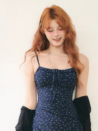 woman in a blue floral mini dress and black cardigan smiling