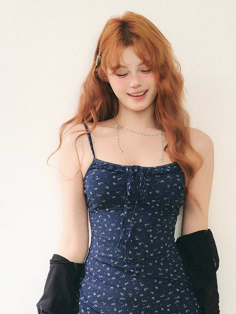 woman in a blue floral mini dress and black cardigan smiling