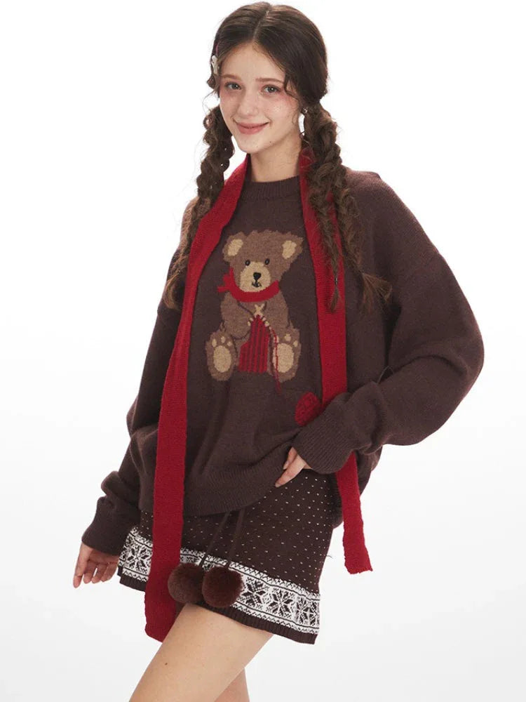 Close-up of a woman wearing a brown knit sweater with a teddy bear graphic and a red scarf