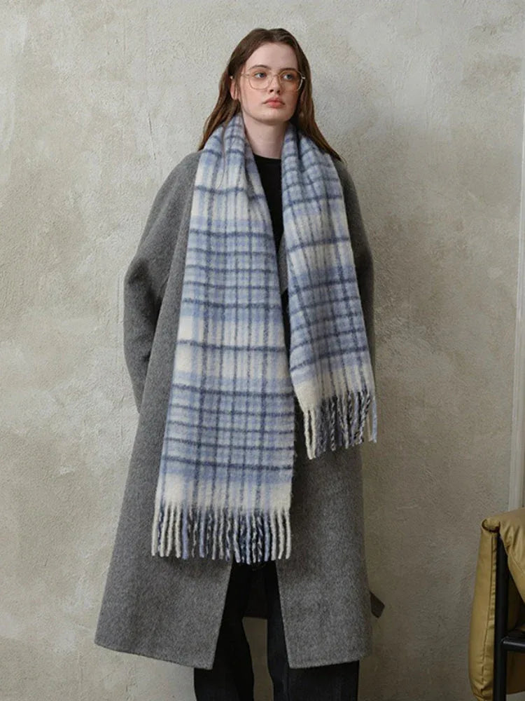Woman wearing a grey coat and a blue and white plaid scarf.