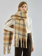 Woman modeling a long, fuzzy knit scarf with a plaid pattern and fringe.