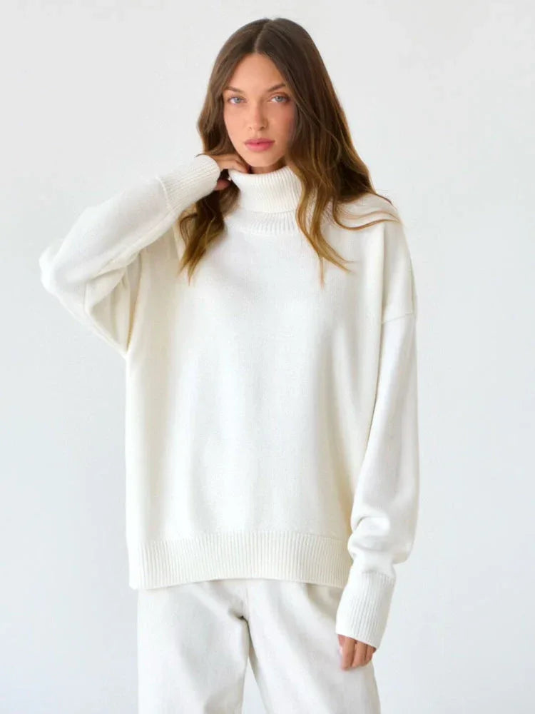 Close-up of a woman wearing a white turtleneck sweater, touching her neck.