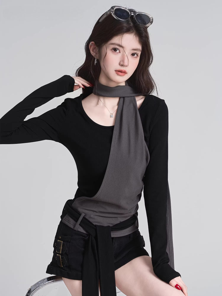 Woman wearing a black long-sleeved top with a grey asymmetrical overlay and scarf detail, facing forward.