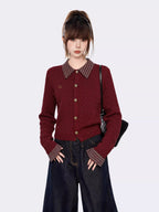 Front view of a woman in a burgundy cable knit cardigan with plaid accents.
