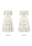 Front view of a white floral print off-the-shoulder tiered dress with puffed sleeves and a bow detail
