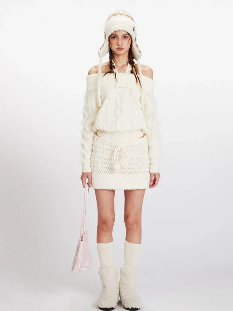 Model wearing a cream off-the-shoulder knit sweater and a matching mini skirt, with an ear flap hat and pink handbag.