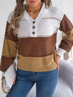 Front view of a woman wearing a brown, tan, and white color block knit sweater with a v-neck and button details, paired with blue jeans and holding a white clutch.