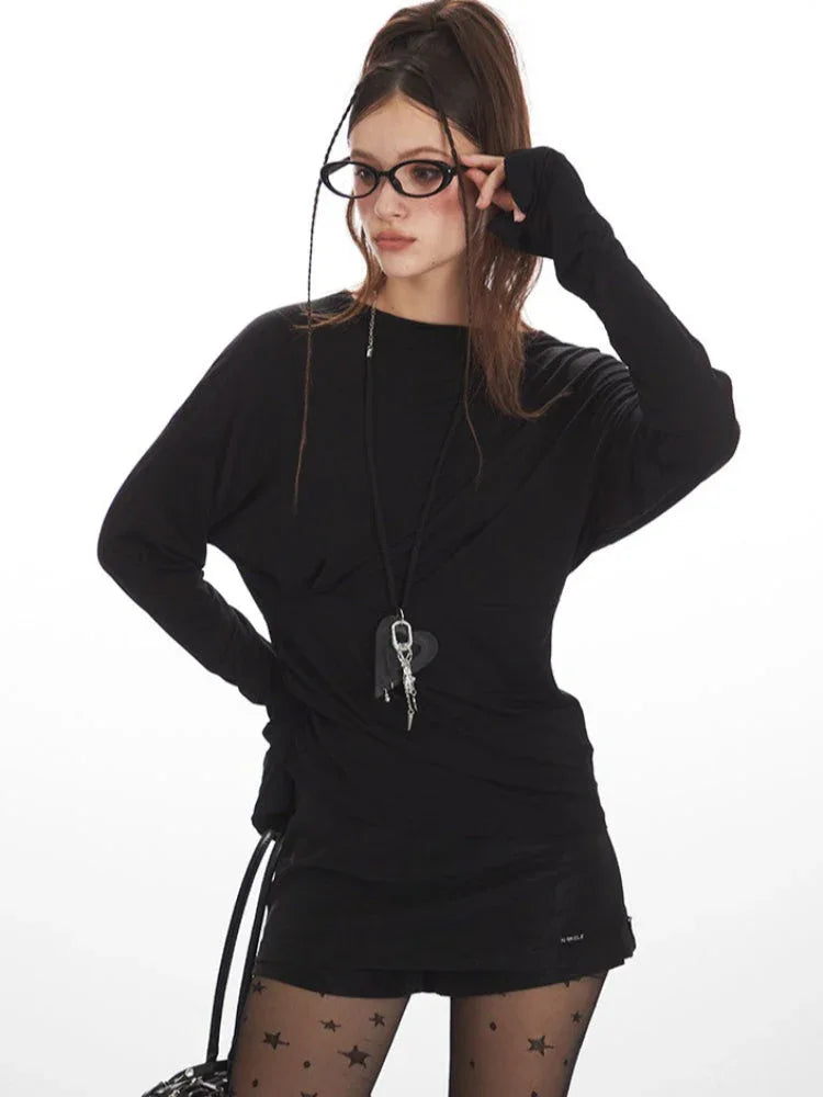 Close-up of a woman wearing a black long-sleeve mini dress, star-patterned tights, and glasses, adjusting her glasses.