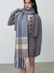 Woman adjusting her plaid scarf over a grey knit dress and cardigan