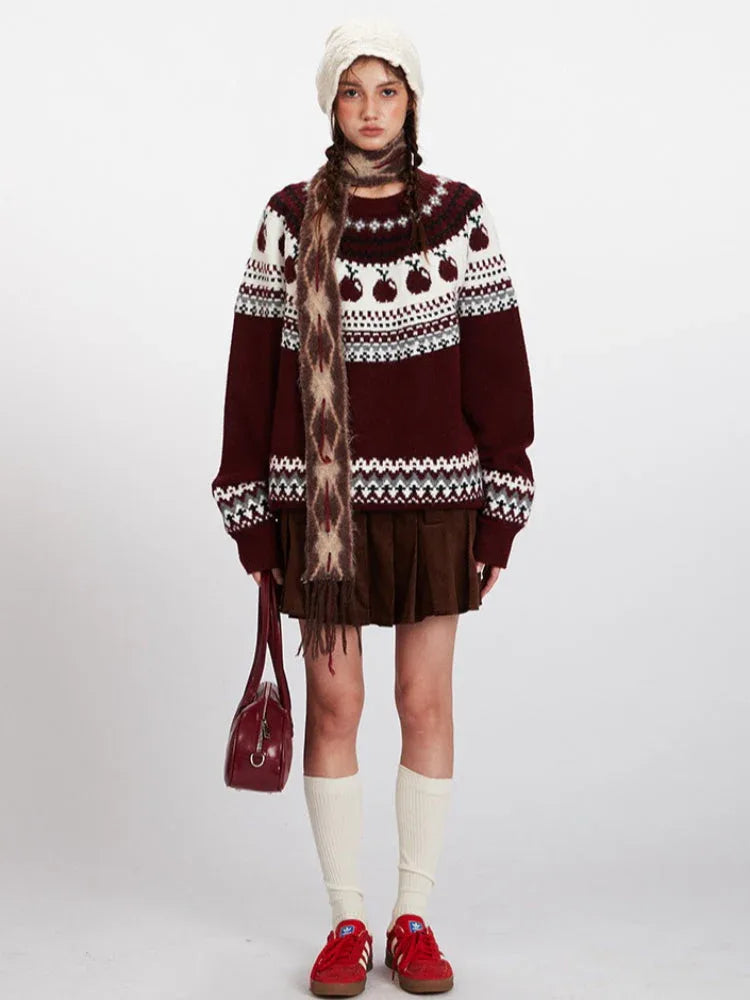 Woman wearing a maroon and white knit sweater with an apple Fair Isle pattern, brown corduroy skirt, white beanie, patterned scarf, white socks, and red sneakers. Main image
