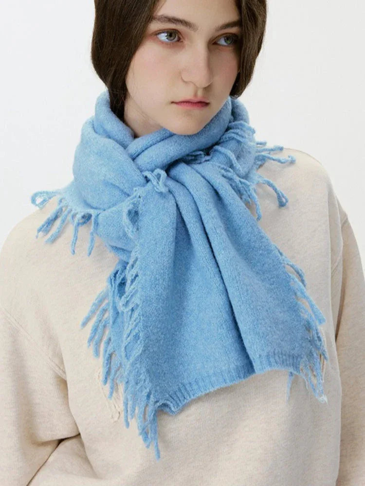 Front view of a woman wearing a light blue scarf with fringe.