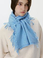 Front view of a woman wearing a light blue scarf with fringe.
