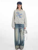 Model wearing a grey graphic print sweatshirt and wide-leg jeans, front view