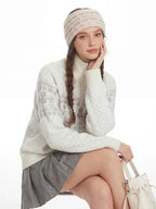 Model sitting down, showcasing the knit sweater, skirt, and accessories.