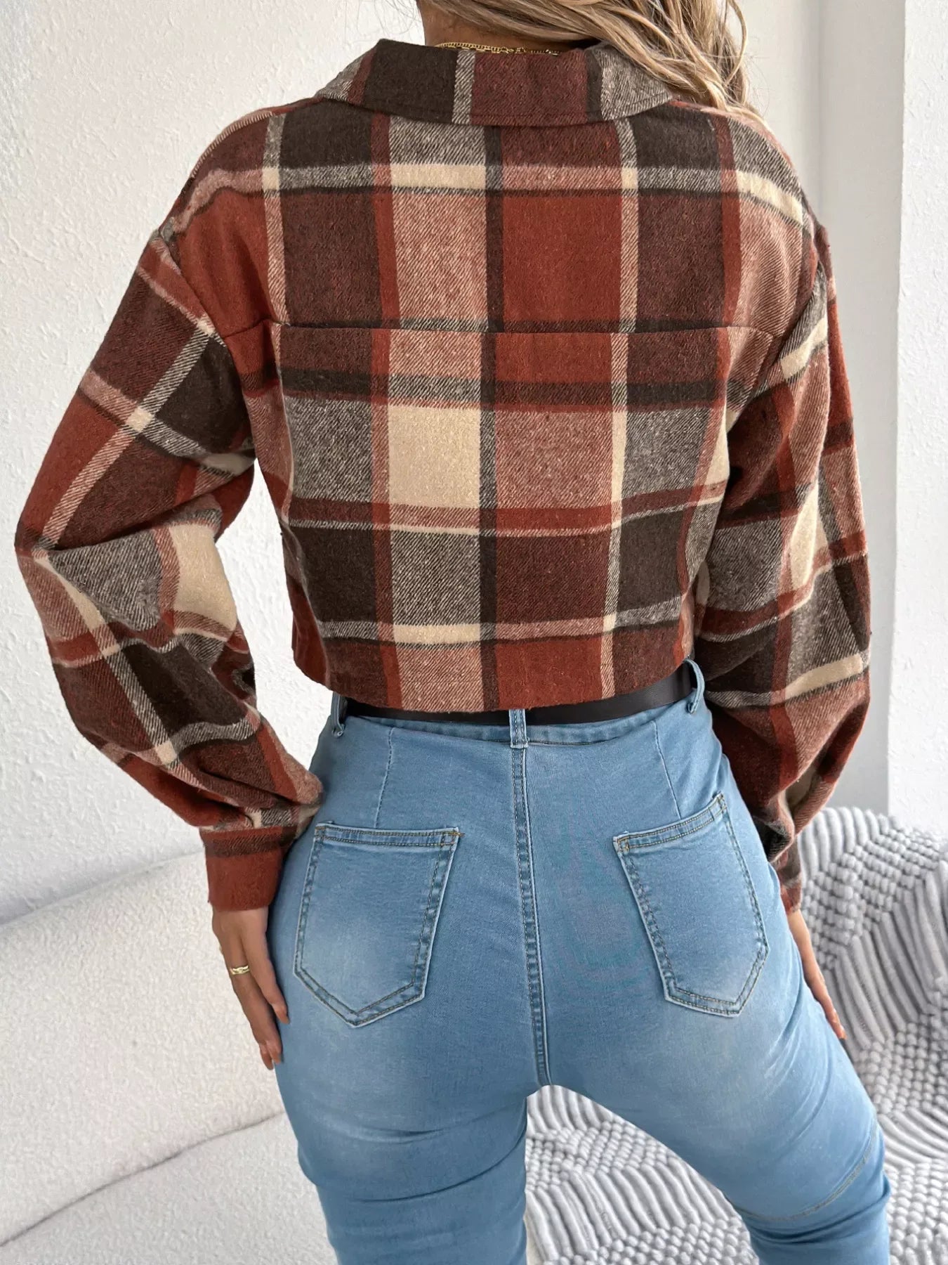 Back view of a model wearing a cropped plaid jacket and blue jeans.
