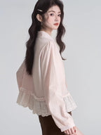 Rear view of a woman wearing a light pink ruffled peplum blouse with a Peter Pan collar and lace trim.