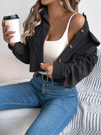 Woman wearing a black corduroy cropped jacket over a white tank top and blue jeans, holding a coffee cup.