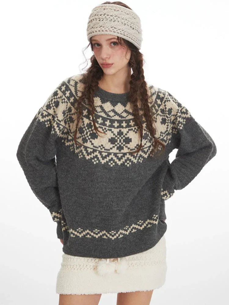 Woman wearing a grey and cream Fair Isle knit sweater and a white headband, posing with hands on hips, front view