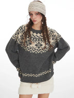 Woman wearing a grey and cream Fair Isle knit sweater and a white headband, posing with hands on hips, front view