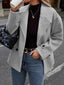 Woman wearing a grey double-breasted wool blend peacoat with a black turtleneck and blue jeans.