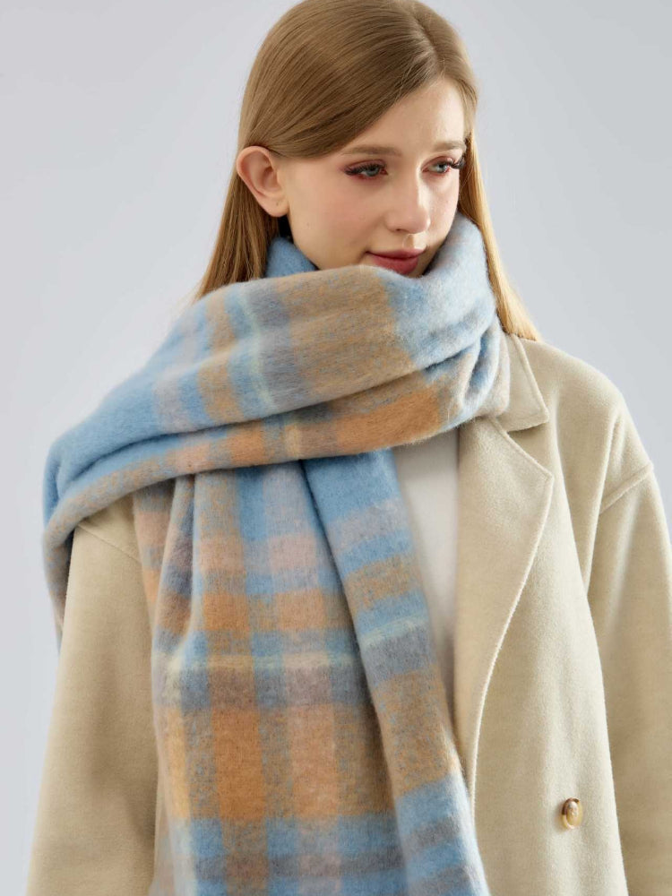 Close-up of a woman wearing a beige coat and a blue and tan plaid scarf.