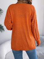 Back view of a woman wearing an orange open-front knit cardigan.
