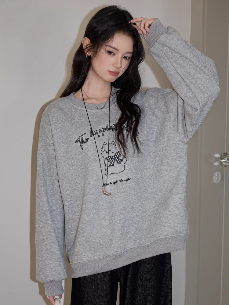 Woman posing with a grey crew neck sweatshirt with a graphic print