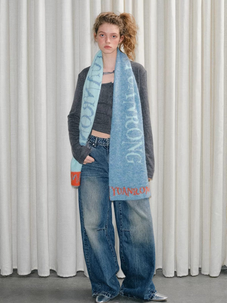 Model posing with hands in pockets, wearing a scarf.