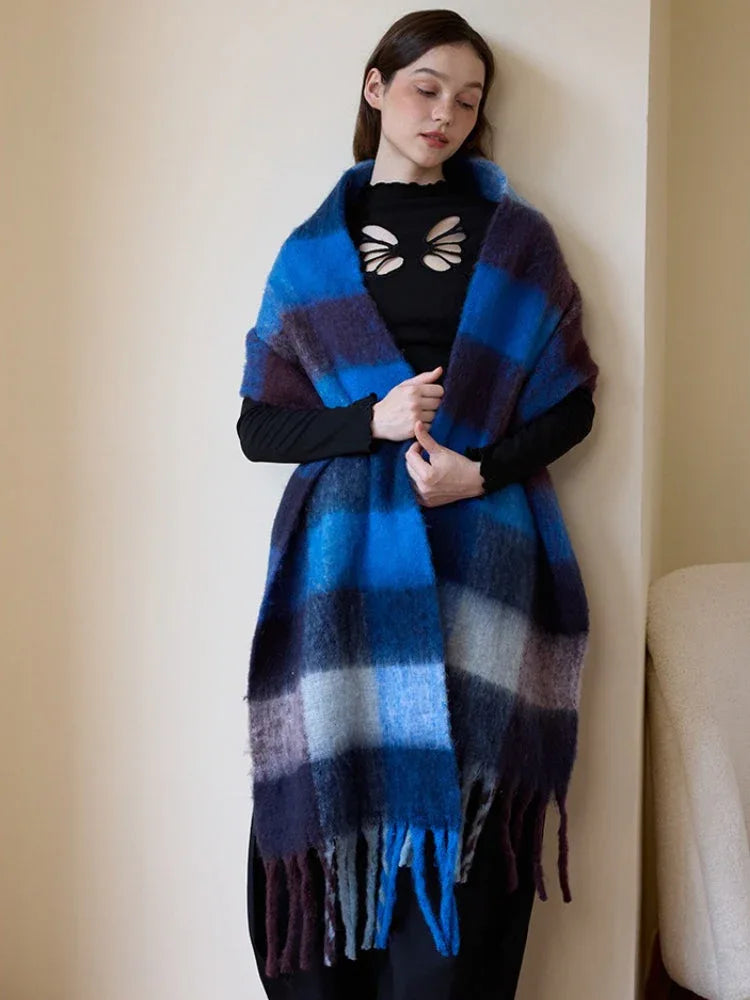 Woman wearing a blue and purple plaid scarf with fringe trim.