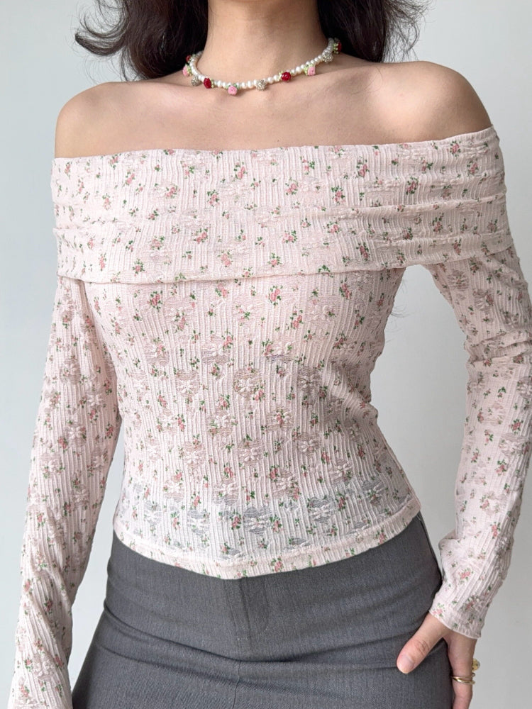 Close-up of a woman wearing a pink floral off-the-shoulder long-sleeved top with a pearl and rose necklace.