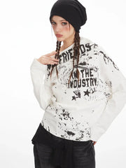 Close-up of a model wearing a white long-sleeved off-the-shoulder top with distressed graphic print, accentuating the neckline.