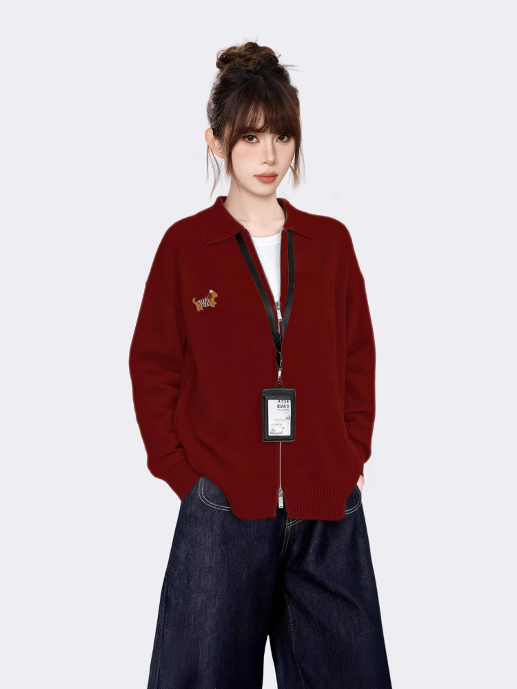 Close-up of the embroidered tiger graphic on the maroon zip-up knit cardigan.