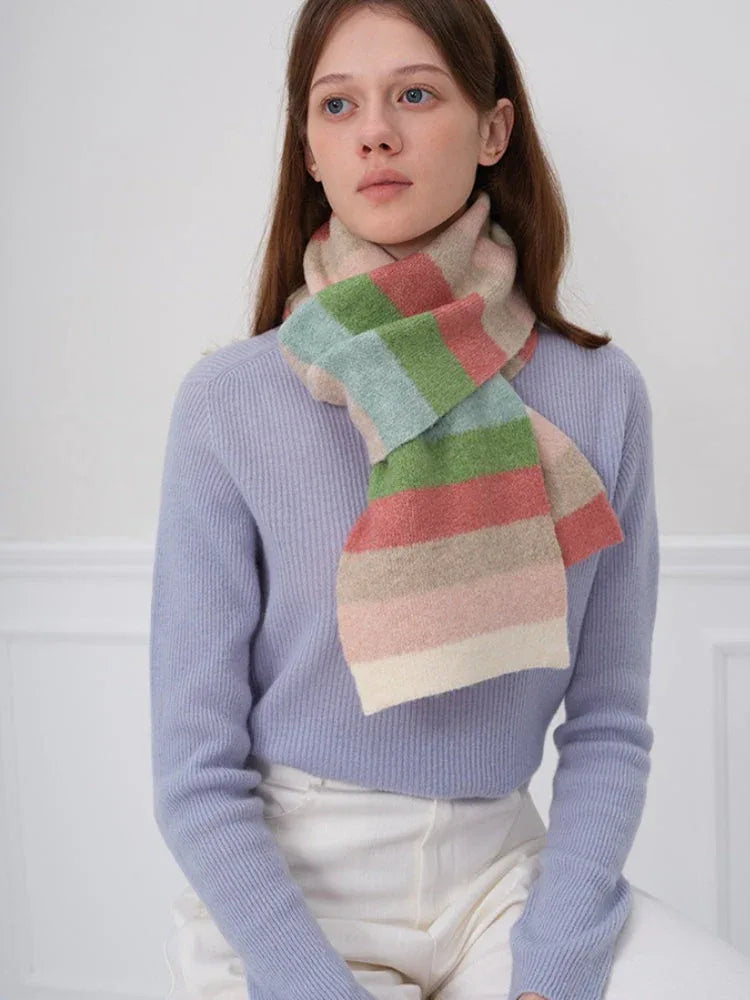 Woman wearing a blue sweater and a pastel striped scarf