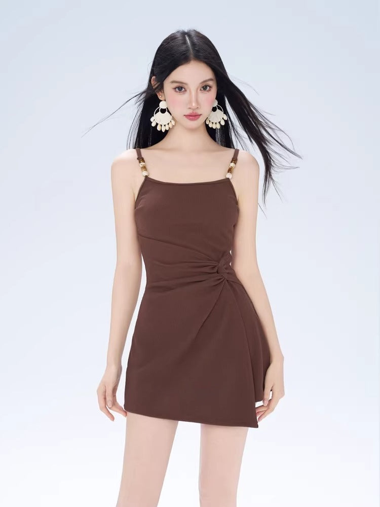 Woman wearing a brown ruched mini dress with a white sheer overlay, viewed from the front.