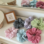 Assortment of colorful gingham scrunchies on a white surface