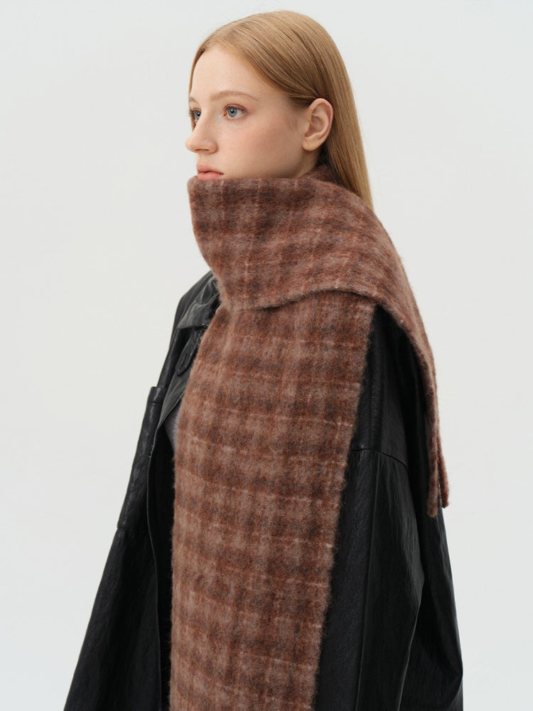 Close-up of a woman's face and shoulders, wearing a brown plaid scarf and a black leather jacket.