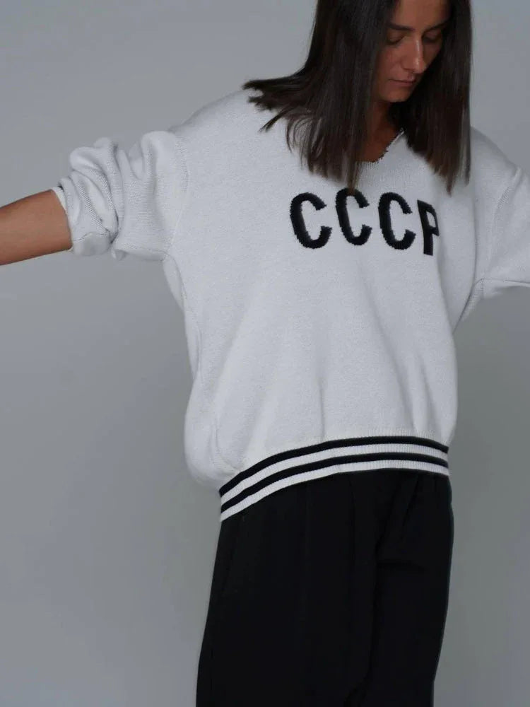 Close-up of a white CCCP knit sweater with black stripes on the cuffs.