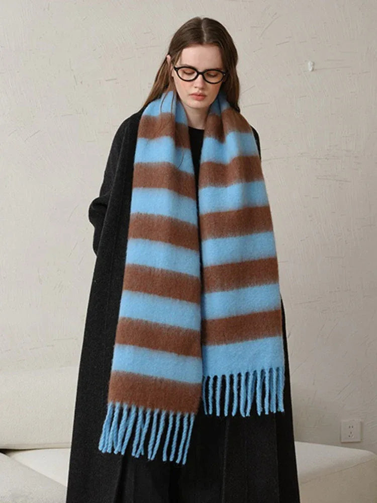 Woman modeling an oversized blue and brown striped scarf with fringe